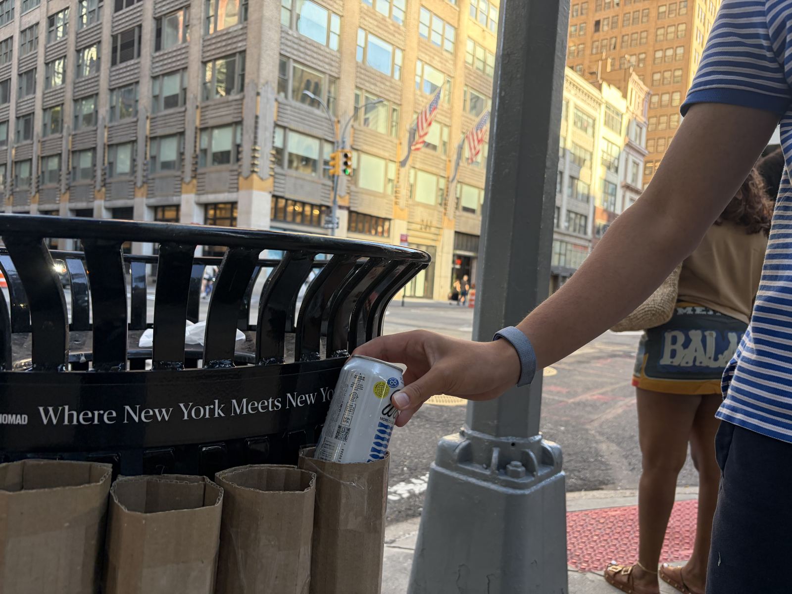 A passer-by dropping a can into the rack on a busy sidewalk