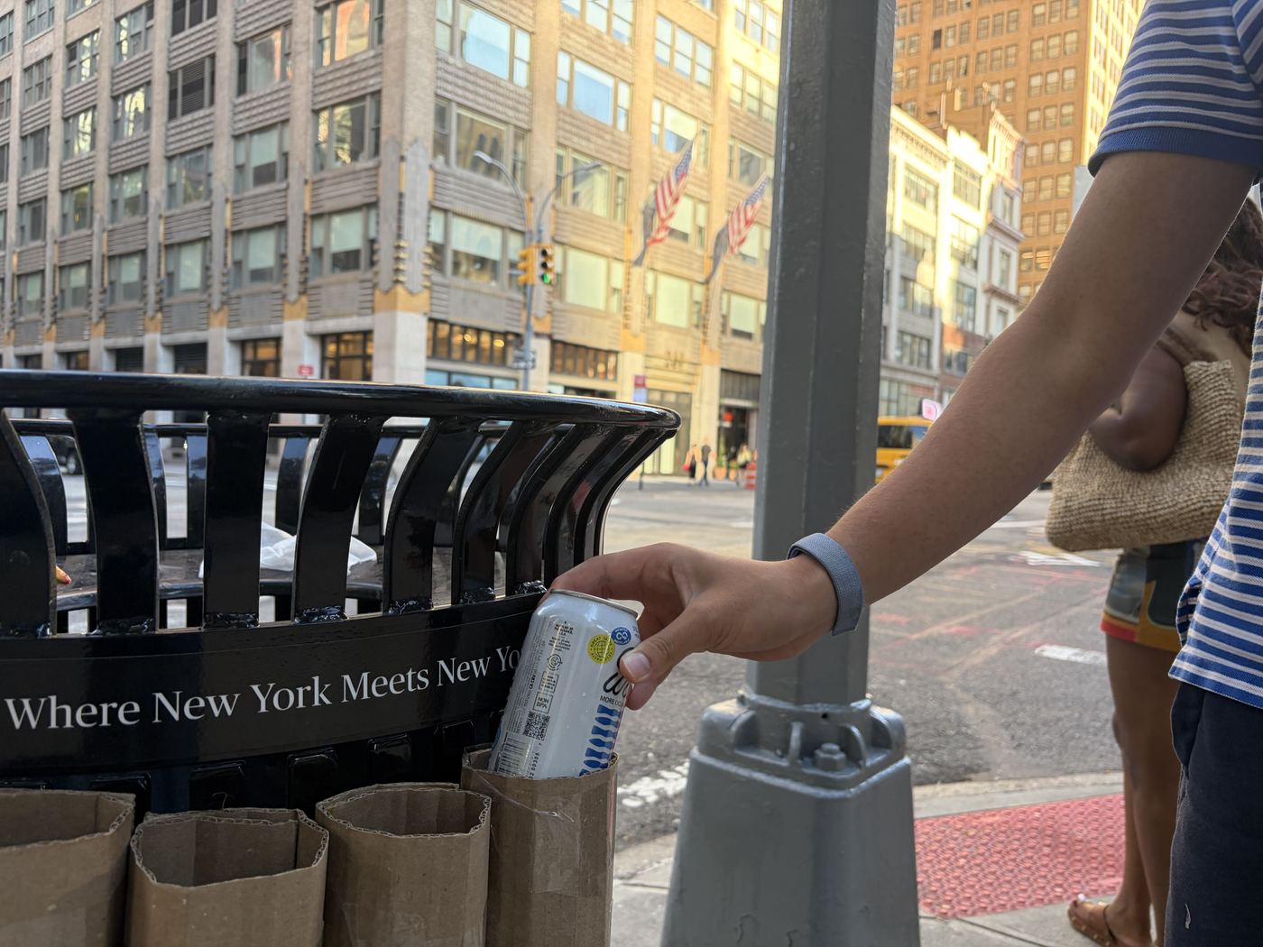 A hand dropping an aluminium can into the top of one of the tubes